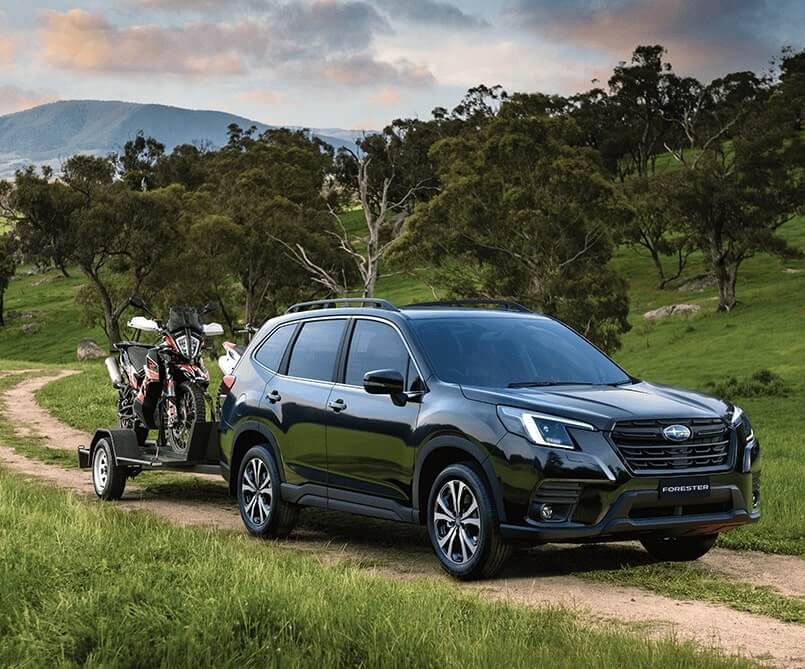 Subaru Forester towing bikes on country road